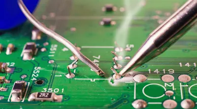 A hobbyist soldering a component on a PCB with a soldering iron