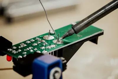 Close up of a soldering iron tip joining a component to a PCB pad