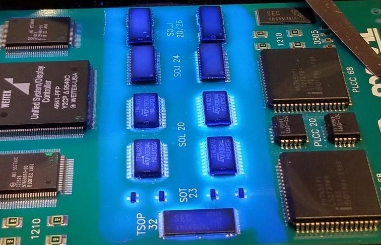 A PCB under UV light for conformal coating defect inspection