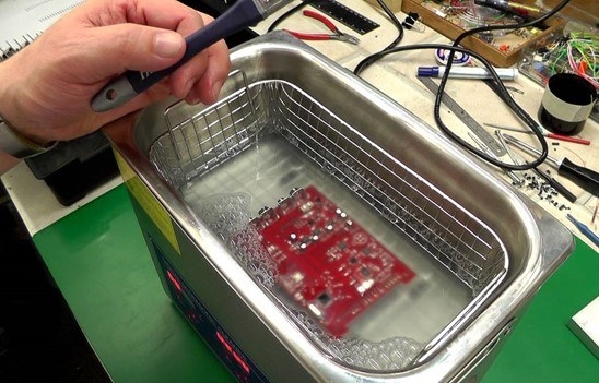 Vibrating bath with PCB immersed for residue agitation