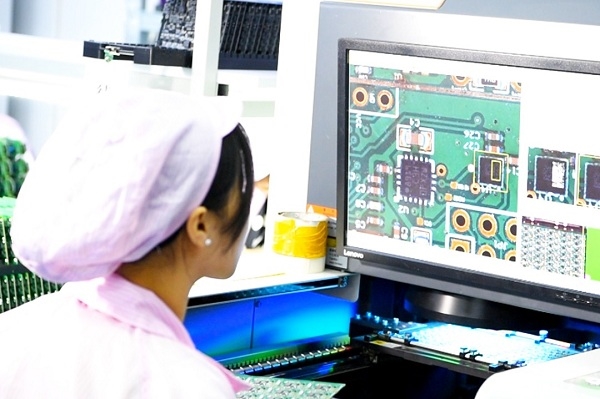 Technician inspecting a PCB assembly line for errors