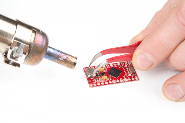 Engineer using a hot air rework station on an IoT PCB