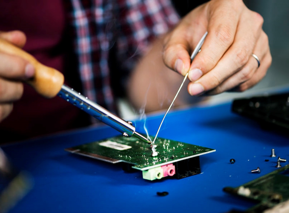 Engineer soldering a component with a soldering iron