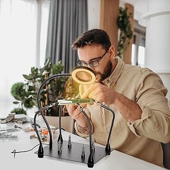 Using a magnifying glass to inspect solder joints on a PCB