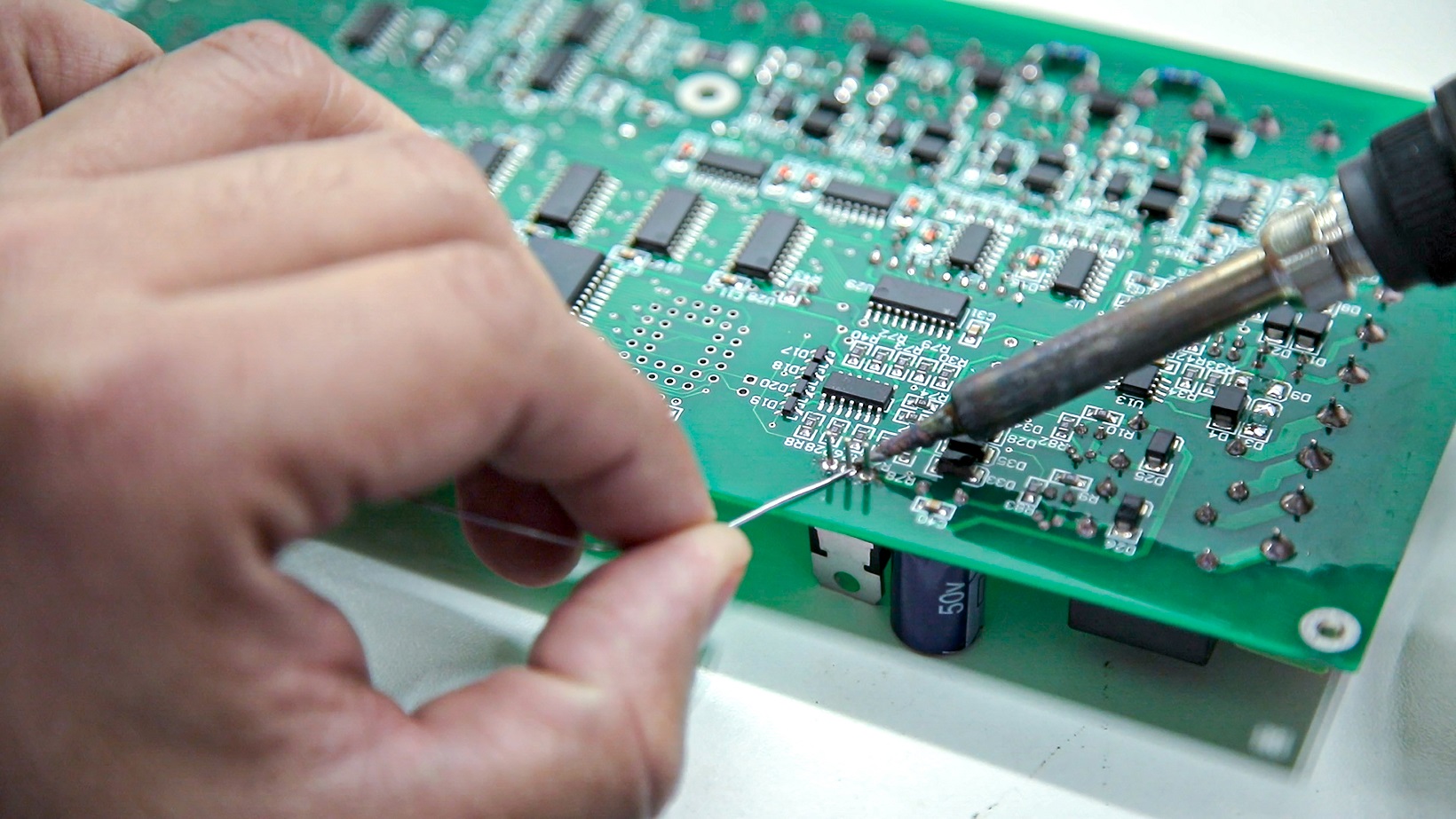 Engineers practicing lead-free hand soldering on PCB samples