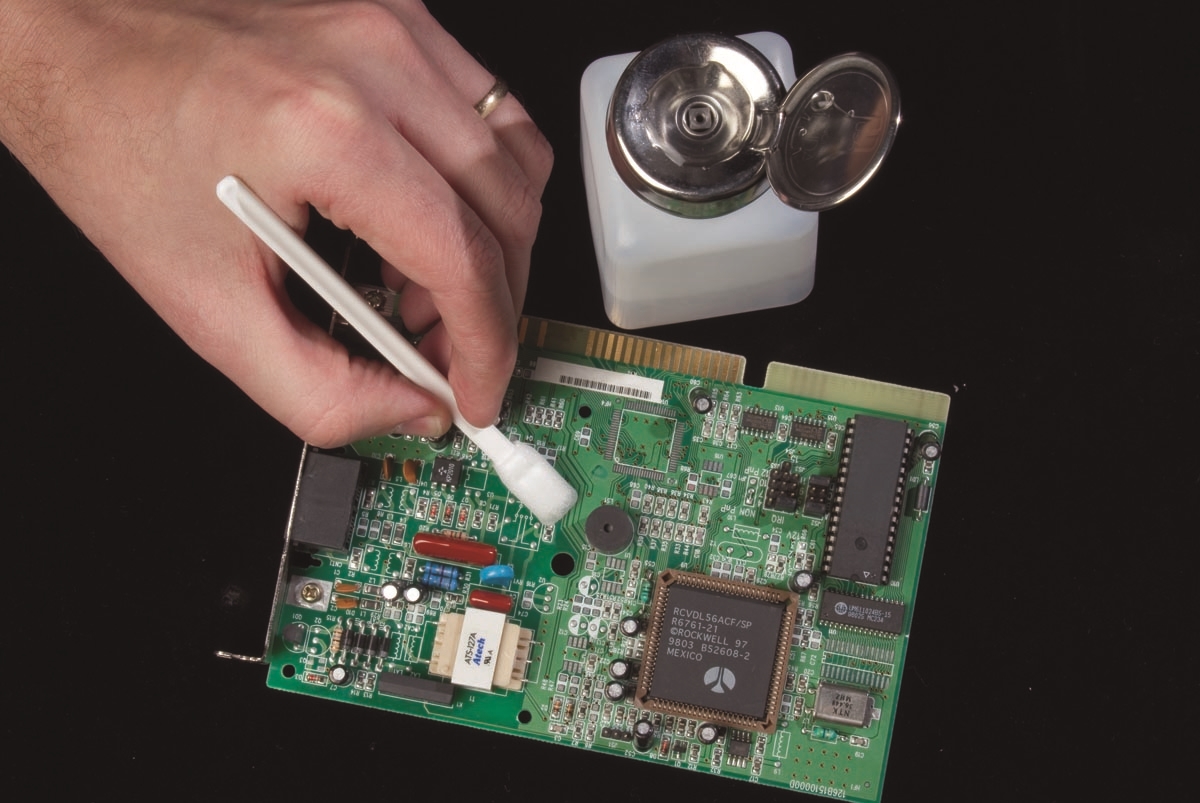 Technician using swab for precise solvent delivery on PCB