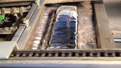Molten recycled tin solder in wave soldering pot during PCB assembly