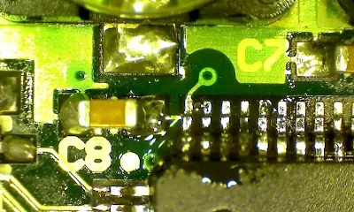 Close-up of flux residues and solder balls on reworked PCB surface