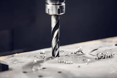 Close-up photograph of a CNC drill bit showing wear on cutting edges next to a cross-section of drilled hole with clean walls versus one with rough edges due to worn tool