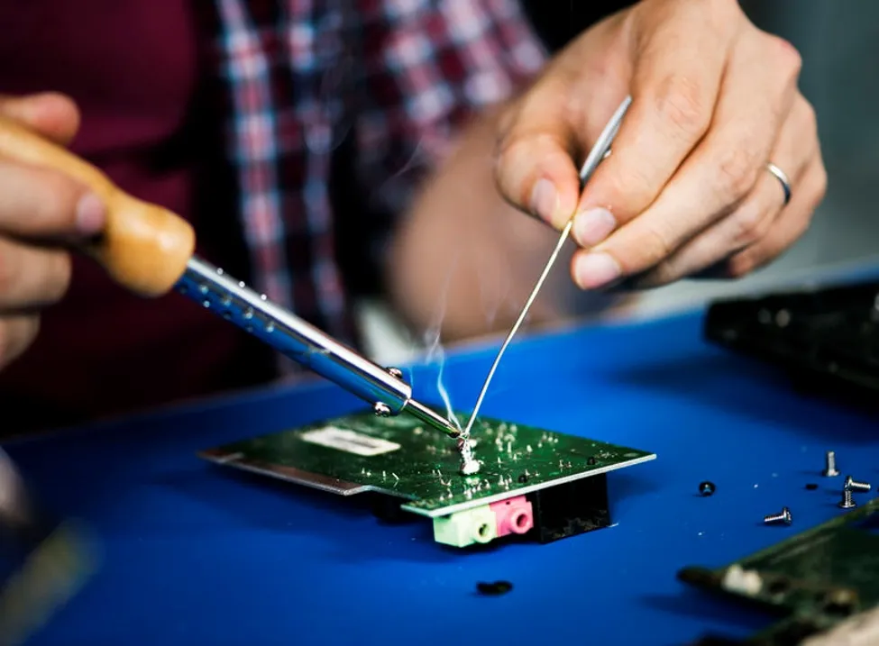 Engineer soldering a component with a soldering iron