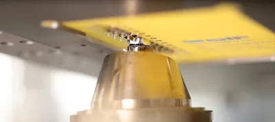 Close-up of a mini-wave solder nozzle applying solder to a PCB