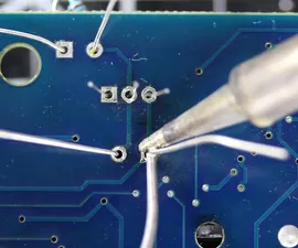 A close-up of soldering a through-hole component on a PCB