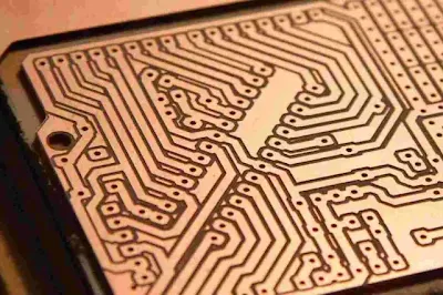 Copper board in etching solution showing trace formation