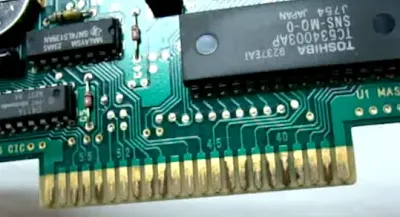 Corrosion appears as tarnishing or pitting on the gold surface, typically resulting from a porous gold layer that fails to protect the underlying metal.