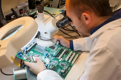 Engineer inspecting a PCB for conformal coating defects under magnification