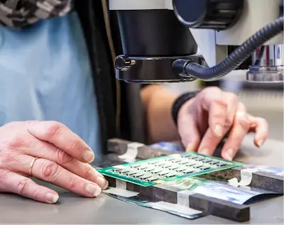 Technician inspecting electronic components under a microscope