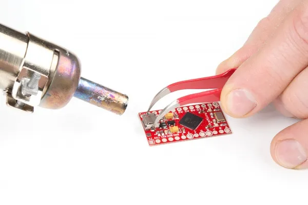 Engineer using a hot air rework station on an IoT PCB