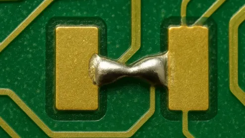Close-up of solder mask bridge in PCB preventing shorts on fine-pitch pads during SMT assembly